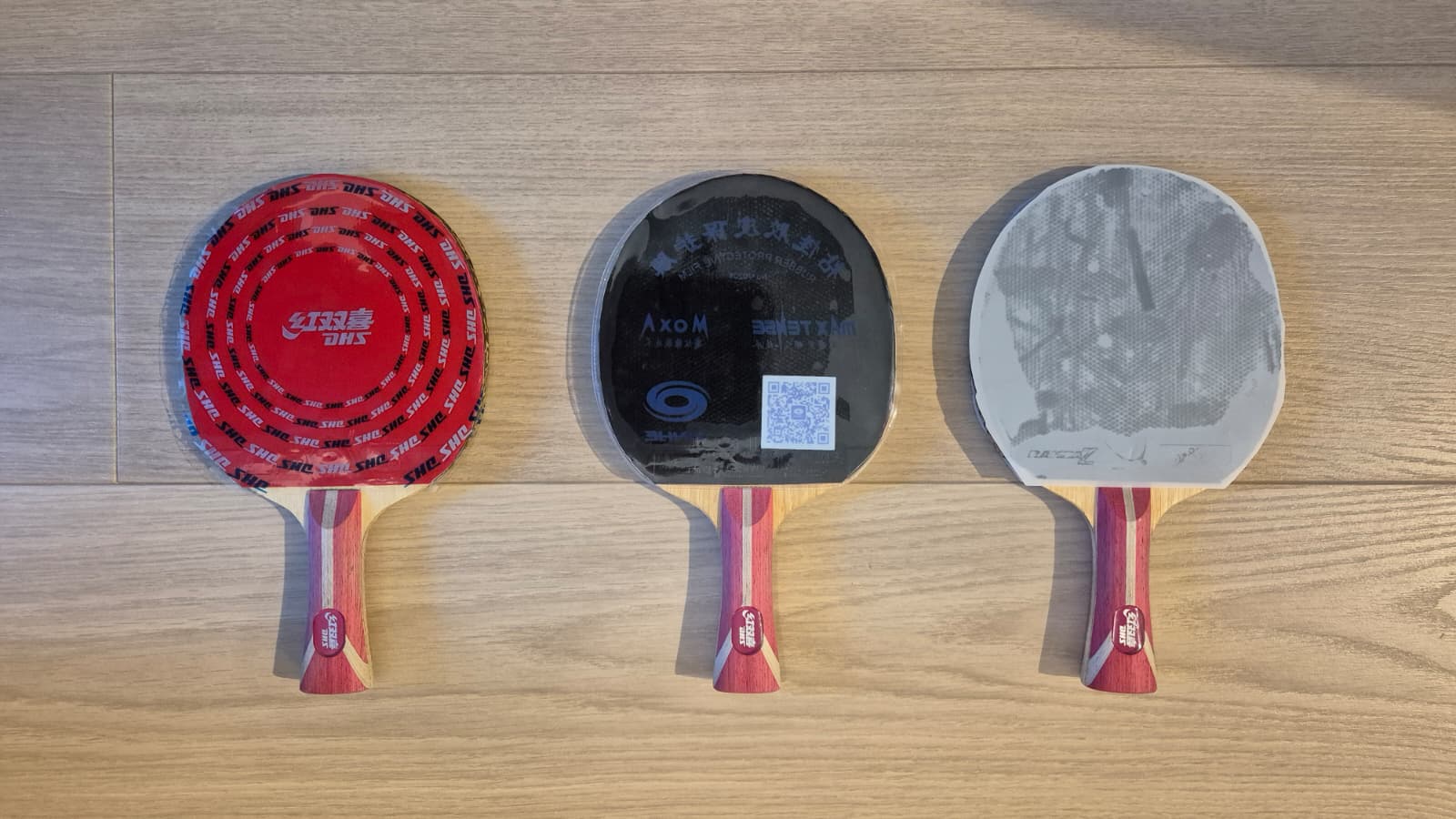 Three DHS Fang Bo B2X blades with different rubbers side by side